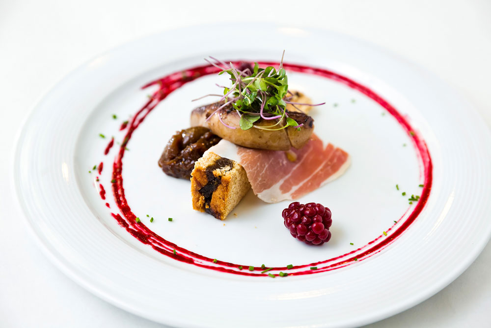 elegantly-plated dish of prosciutto, foie gras, and cranberry topped with greens